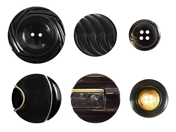 Isolated photo of various black and ivory plastic decorative cloth buttons or rivets on white background.