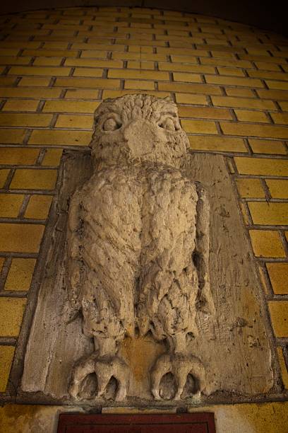 A stone carving of an owl on a brick wall, showcasing intricate details and textures