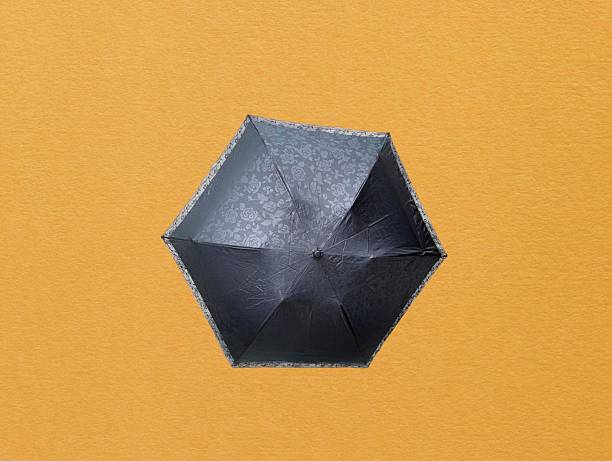 The yellow background in the picture is a black umbrella with a flower and leaf pattern. The frame is made of black silver aluminum with a beautiful pattern. There is a hanging hook with a flower.