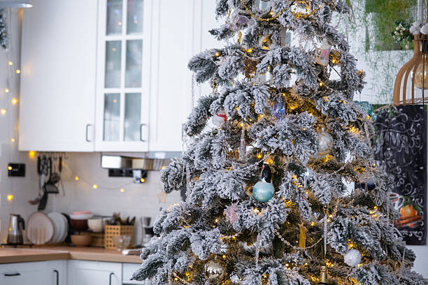 istock Christmas decor in white kitchen, mess dishes, contemporary interior with a snowy Christmas tree and gold fairy lights. New Year, Christmas mood, cozy home. 2247719362