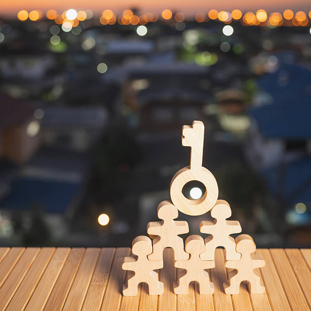 istock Wooden team figures forming a pyramid with a key symbol on top, representing teamwork, leadership, and success. Ideal for business strategy, goal achievement, and corporate concepts. 2247722549