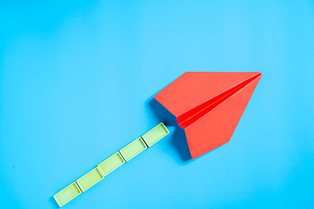 Red paper airplane with rectangular blocks on a blue background. Concept of travel, exploration, and navigation