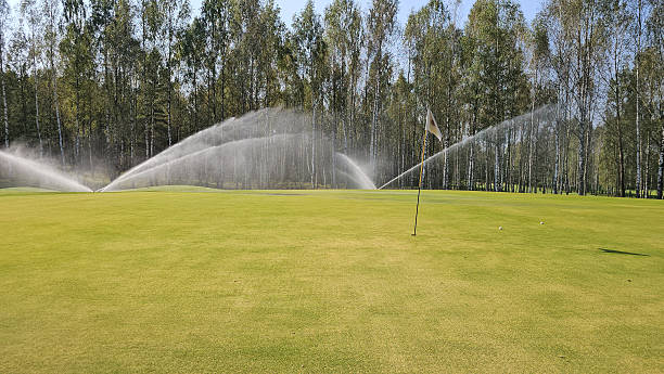 istock Golf course maintenance with sprinklers operating on a sunny day in a tranquil green landscape concept 2247729499