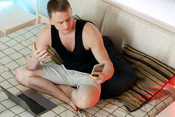 istock Relaxed man with arm behind head, using phone and laptop 2247732460