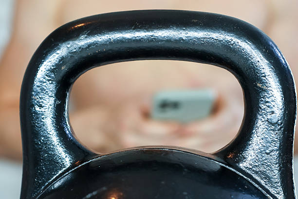 Person holding smartphone seen through kettlebell handle