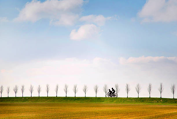 Netherlands Holland couple riding bicycles on dike.