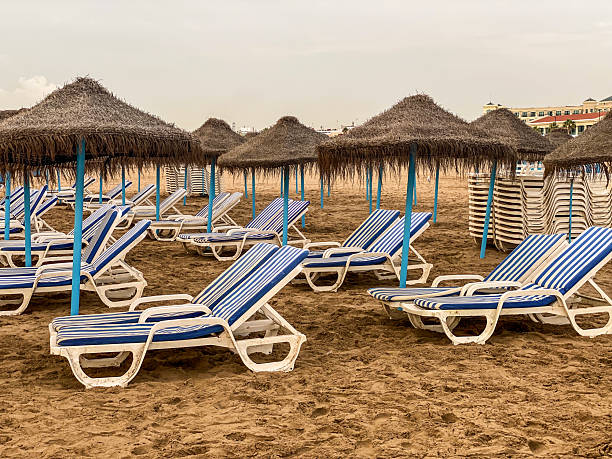 Resort. Beach umbrella on north shore of the Lake Issyk-Kul  and view on high snow covered mountain peaks Tien Shan on south shore, Kyrgyzstan