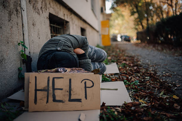 istock Homeless man sleeping on street with help sign 2247736818