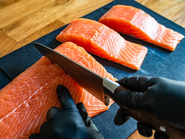 istock Cutting raw salmon fillet on wooden background 2247740175