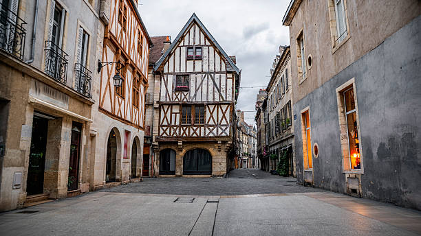 Historic center of Dijon, France, featuring a classic medieval timber-framed house surrounded by traditional stone buildings. The quiet pedestrian street, overcast sky, and preserved architecture highlight the old-world character and cultural heritage of Burgundy’s capital city. Dijon in the Bourgogne-Franche-Comté region in eastern France.