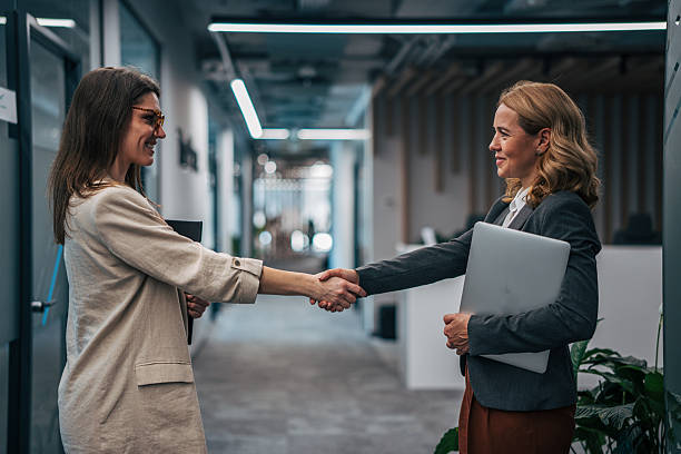 istock Businesswomen shaking hands in modern office hallway 2247744261