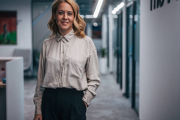istock Confident businesswoman smiling in modern office hallway 2247744317