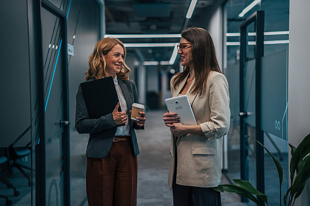 istock Businesswomen talking in modern office hallway 2247744608