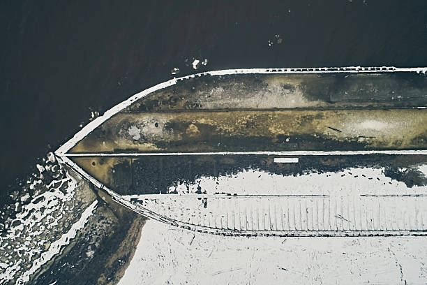 Aerial view of an abandoned wooden ship at the bottom of the river in winter against the backdrop of white snow and black water close-up