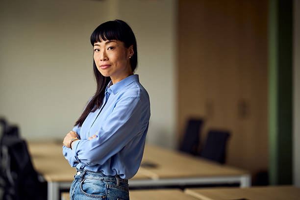 istock Asian Woman In Light Blue Shirt Stands Confidently In Modern Workspace Office Setting 2247753543