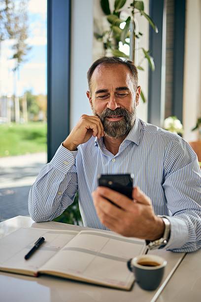 istock Man in Striped Shirt Enjoys Coffee While Using a Smartphone in a Bright Cafe 2247753549