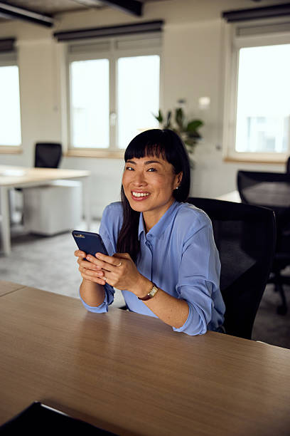 istock Smiling Office Professional With Smartphone At Desk In Bright Modern Workspace 2247753551