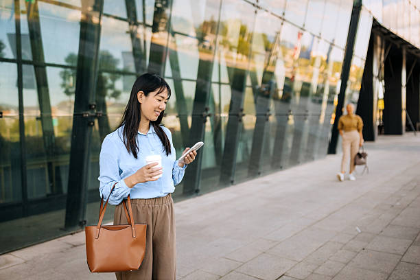 istock Well dressed smiling businesswoman using smart phone while standing in front of modern building 2247753790