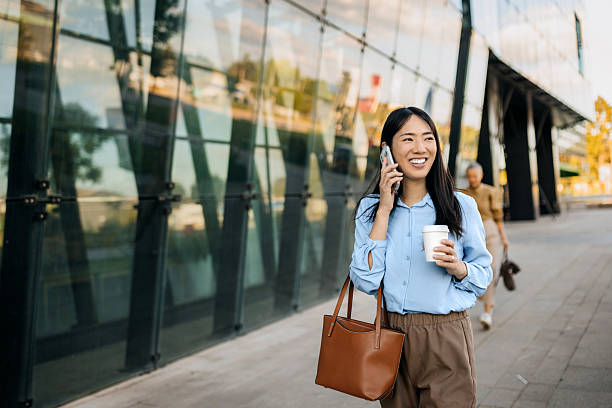 istock Well dressed smiling businesswoman using smart phone while standing in front of modern building 2247753869