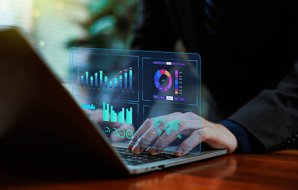 istock Business professional working on a laptop with futuristic digital dashboards displaying analytics, financial data, charts, and global metrics, highlighting advanced data analysis and innovation. 2247754316