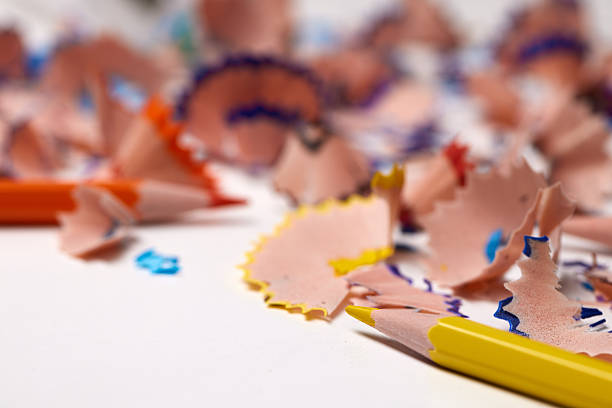 Pencil shavings with colorful lead remnants lying on a white surface