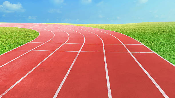 istock An empty red running track at the stadium, surrounded by lush green grass. 2247758567