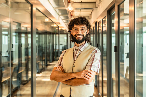 istock Young man smiling and standing in modern office corridor 2247758976
