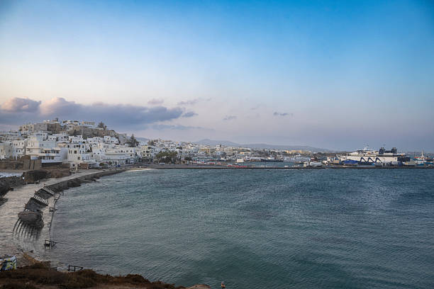 Early morning light over a Cycladic seaside town on Naxos, Greece, with calm waters, traditional white buildings, and the port in the distance.