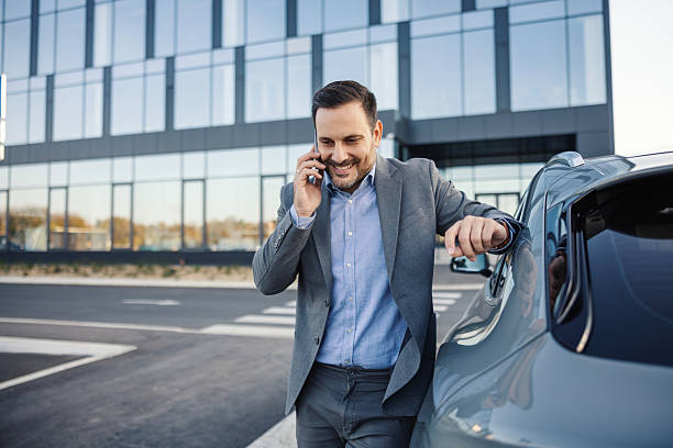 istock Smiling businessman talking on phone leaning on car 2247760303