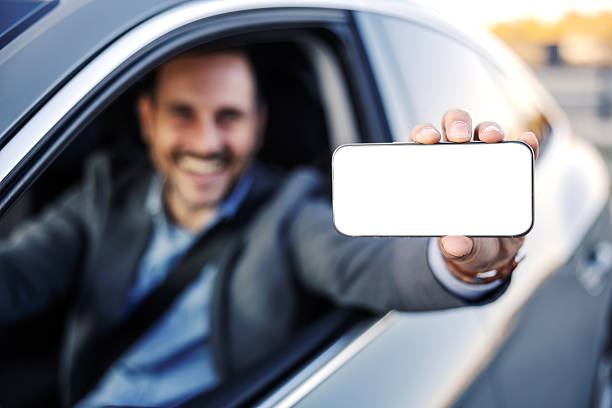 istock Businessman showing blank smartphone screen from car window 2247760942