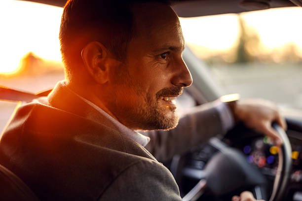 istock Smiling man driving car on road trip during sunset 2247760965