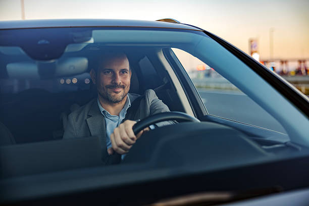 istock Smiling businessman driving car during evening commute 2247760990