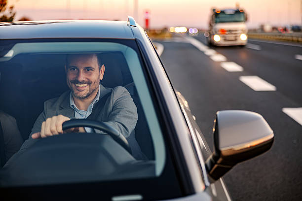 istock Man driving car on highway smiling after work 2247760994