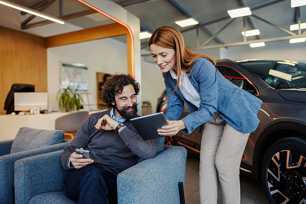 istock Saleswoman assisting customer choosing new car using tablet 2247762078
