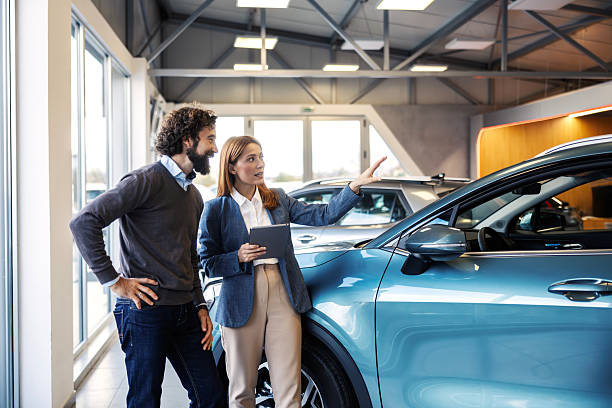 istock Saleswoman explaining car features to customer in showroom 2247762090
