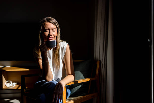 istock Calm Morning Moment: Woman Sips Coffee in Soft Sunlight at Home 2247762208