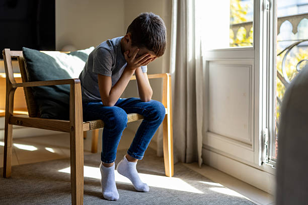 istock Sad Boy Sitting With Face In Hands By Window, Reflective Moment At Home 2247762280
