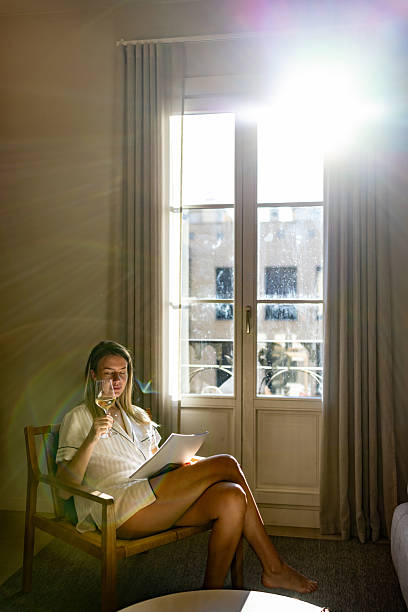 istock Woman Relaxing With Wine While Reading Papers By Bright Window In Soft Morning Light 2247762382