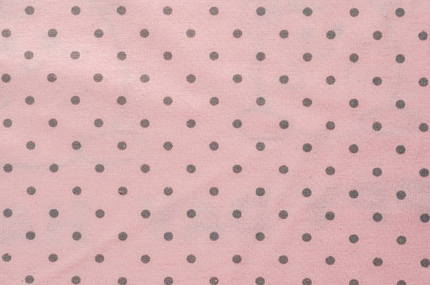 Soft pink texture with white polka dots creates a delicate and playful background.