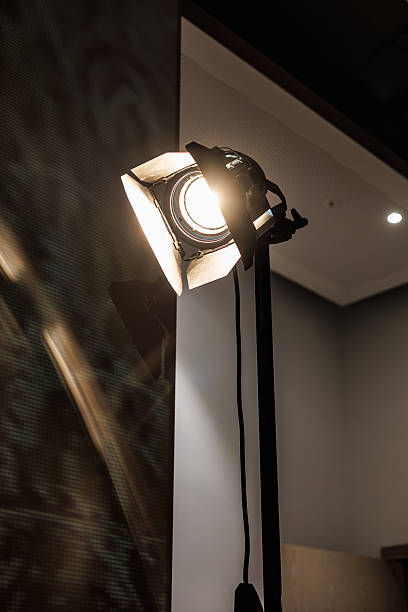 istock A professional studio spotlight turned on, mounted on a stand in a modern indoor environment with ceiling lights and textured wall reflections 2247763884
