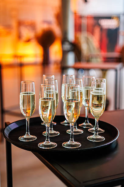 istock A black tray holding multiple champagne flutes filled with sparkling wine, set on a dark table with a warm, blurred background. Ideal for event or hospitality themes 2247763995