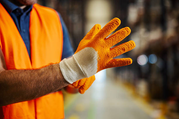 istock Worker hands putting on orange safety gloves in warehouse 2247764302