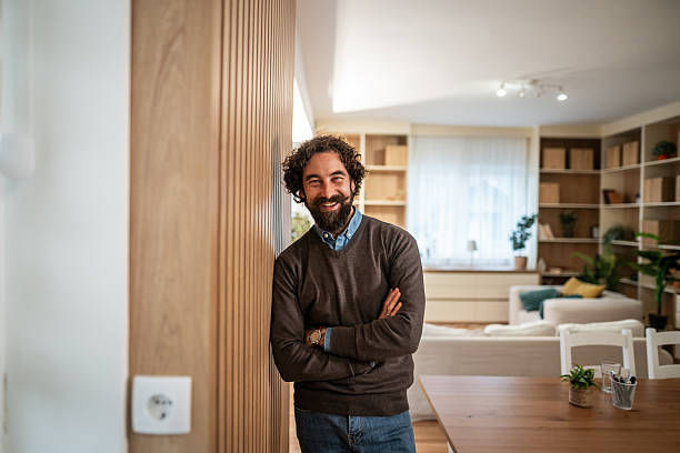 istock Smiling man standing with arms crossed at home 2247764780
