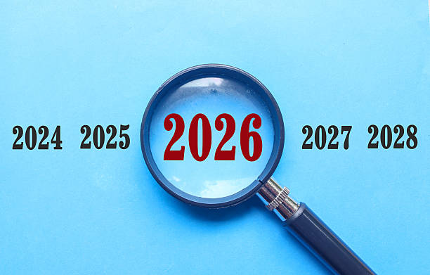 istock New Year 2026 is enlarged using a magnifying glass on blue background. 2026 highlighted through a magnifying glass, with 2025 and 2027 displayed on each side 2247769028