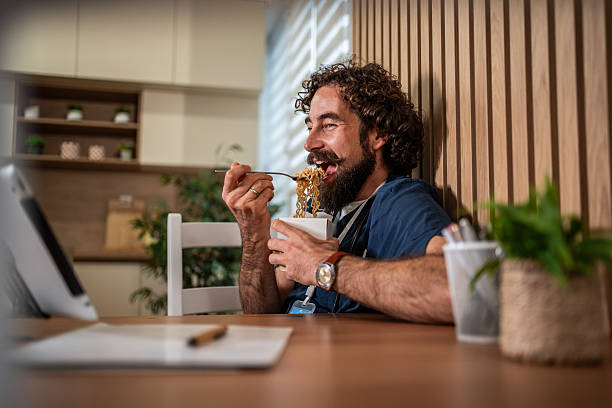 istock Happy man eating noodles enjoying quick lunch break 2247774259