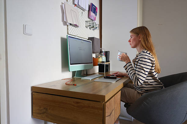 istock Remote work concept, woman using computer at modern wooden desk with coffee mug. 2247777168