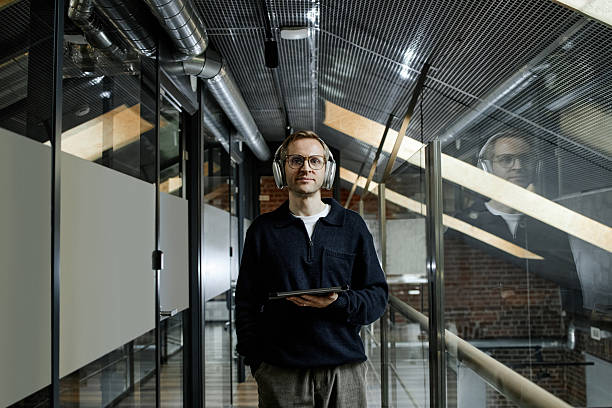 istock Young Caucasian Man Wearing Headphones Using Digital Tablet in Modern Office 2247777354