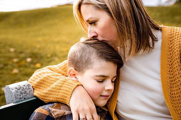 istock mother consoling child boy in the autumn leaf fall sit on bench 2247777929