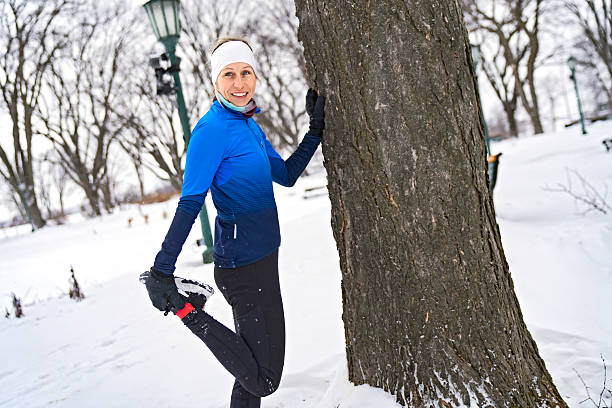 A Nice stretching Young Woman Running in Snowy Park