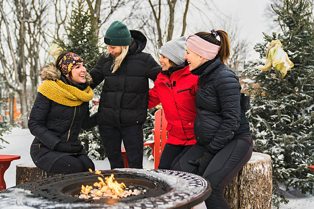 istock friends in winter coats sitting fire in forest 2247779746